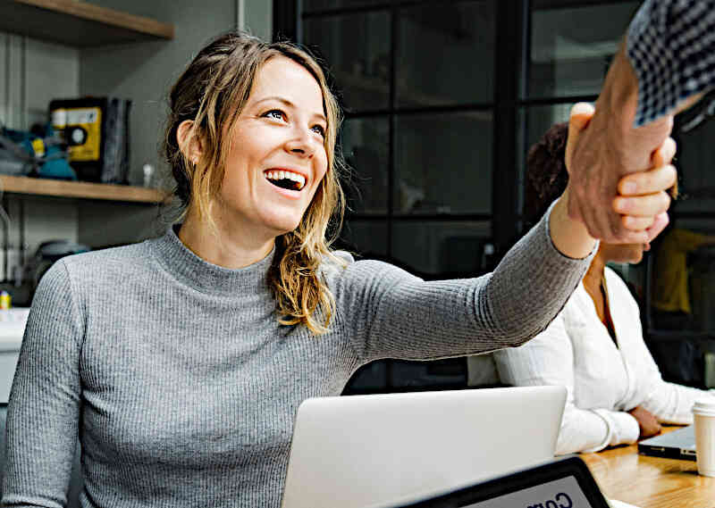Frau in einem Büro gibt einem Kunden die Hand | Symbolbild