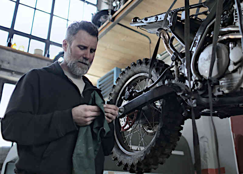 Ein Mann in einer Fabrikhalle repariert ein Motorrad | Symbolbild